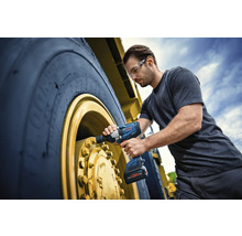 Ein Mann benutzt einen Akku-Drehschlagschrauber an einem großen Reifen eines Nutzfahrzeugs.