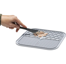 Graue Futtermatte mit Futter und Hand mit Messer