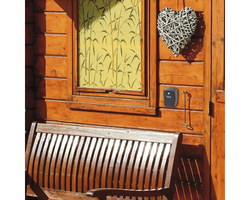 Schlüsselkasten mit Zahlencode an einer Holzwand neben einer Holzbank