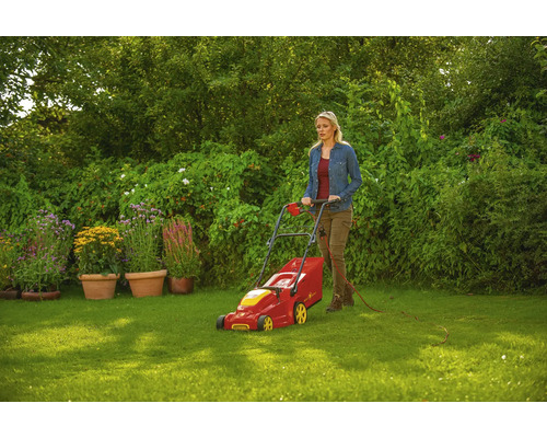 Frau bedient einen Rasenmäher im Garten.
