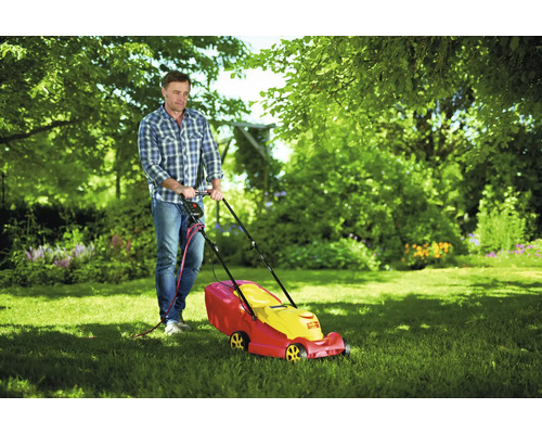 Mann mäht Rasen mit einem Rasenmäher im Garten.
