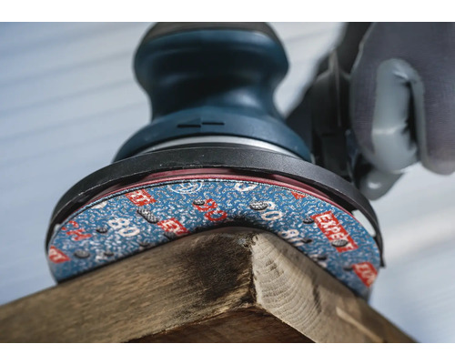 Detailansicht eines Schleifgerätes beim Bearbeiten eines Holzstücks.