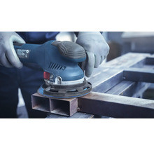 Eine Person schleift mit einem Exzenterschleifer ein Metallstück.