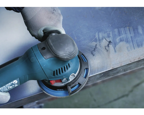 Eine Hand mit Handschuh schleift eine Metallplatte mit einem Exzenterschleifer.