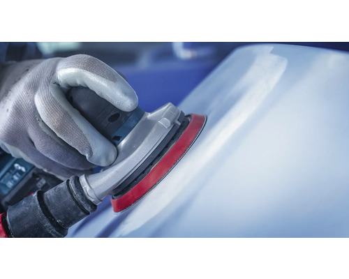 Hand mit Schutzhandschuh schleift mit einem Exzenterschleifer eine Oberfläche.