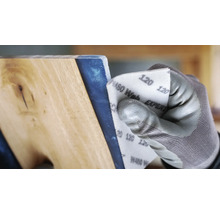 Eine Person schleift ein Holzbrett mit Schleifpapier der Körnung 120.