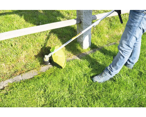 Rasentrimmer im Einsatz zum Schneiden von Gras entlang eines Zauns.