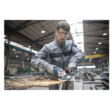 Ein Arbeiter mit Schutzbrille verwendet einen Winkelschleifer auf Metall und erzeugt Funken.