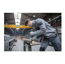 Ein Mann schleift Metall mit einem Winkelschleifer in einer Werkstatt.