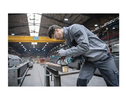 Ein Mann schleift Metall mit einem Winkelschleifer in einer Werkstatt.