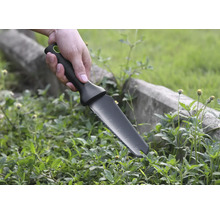 Hand hält Gartenmesser zum Jäten von Unkraut.