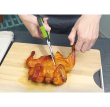 Hähnchen wird mit einer Geflügelschere auf einem Schneidebrett zerteilt.