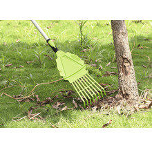 Gartenrechen zum Entfernen von Laub auf Rasenfläche neben Baumstamm