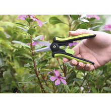Gartenschere in einer Hand vor Pflanzen