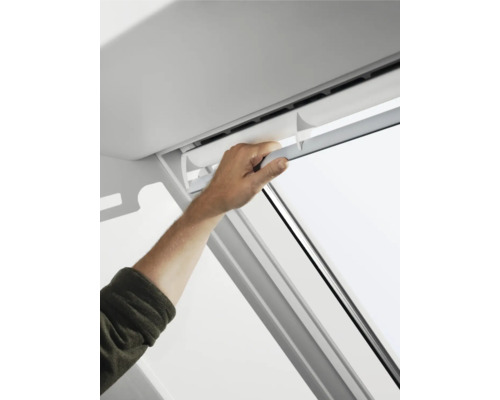 Eine Person bedient ein Dachfensterrollo.