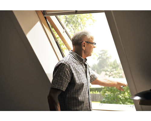 Ein Mann schaut aus einem Dachfenster