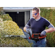 Mann schneidet Hecke mit einer elektrischen Heckenschere von Einhell.