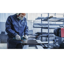 Ein Handwerker schleift Metall mit einem Exzenterschleifer, ausgestattet mit Sicherheitsausrüstung.