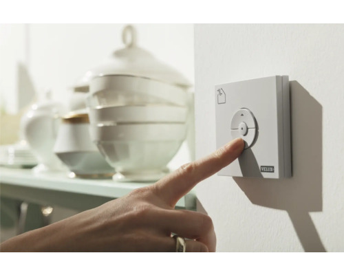 Eine Hand bedient einen VELUX Wandschalter zur Steuerung von Dachfenstern