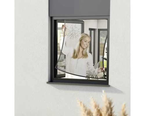 Frau installiert ein Insektenschutzgitter in einem Fenster.