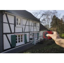 Hand verwendet einen Laser Entfernungsmesser an einem Fachwerkhaus