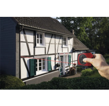 Eine Person verwendet ein Laser-Messgerät an einem Haus, um eine horizontale Linie anzuzeigen.