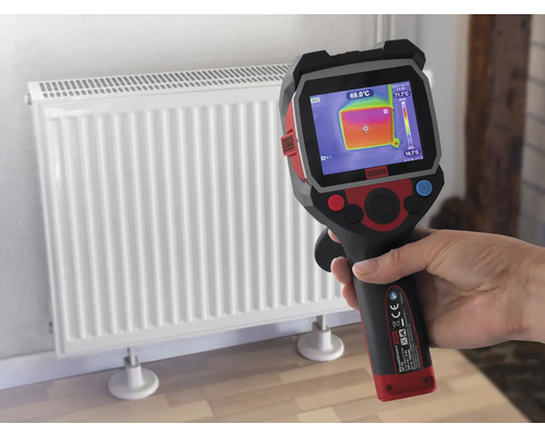 Eine Hand hält eine Wärmebildkamera vor einen Heizkörper, um die Temperatur zu messen.