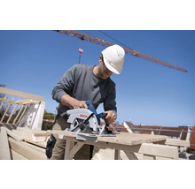 Ein Bauarbeiter benutzt eine Handkreissäge auf einer Baustelle.