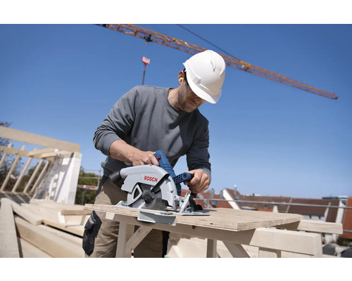 Ein Bauarbeiter benutzt eine Handkreissäge auf einer Baustelle.