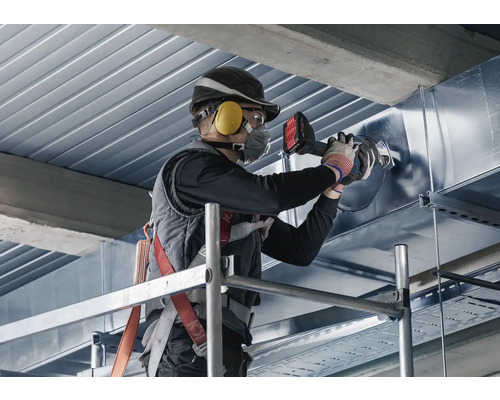 Ein Mann arbeitet auf einem Gerüst mit einer Rohrbiegemaschine an einem Metallrohr.