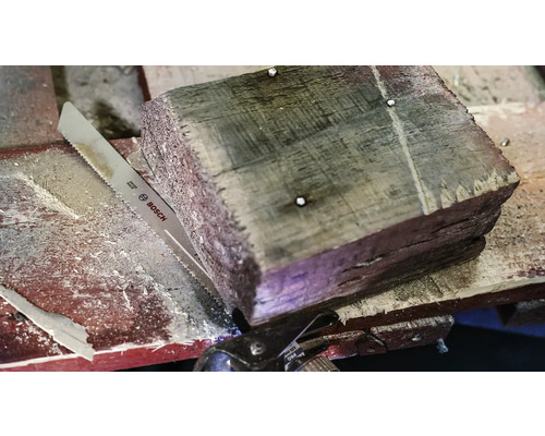Holzstück mit Metallsäge und Bosch Logo.