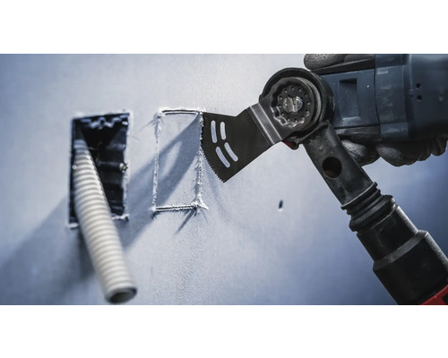 Oszillierendes Elektrowerkzeug schneidet eine quadratische Form in eine Wand neben einer Öffnung mit einem Kabel