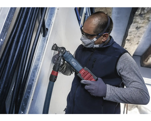 Ein Handwerker benutzt ein Multifunktionswerkzeug zum Schneiden in einer Wand