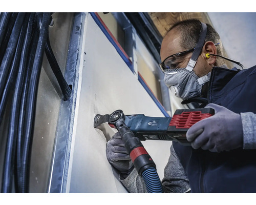 Handwerker schneidet mit einem Multifunktionswerkzeug ein Loch in eine Trockenbauwand