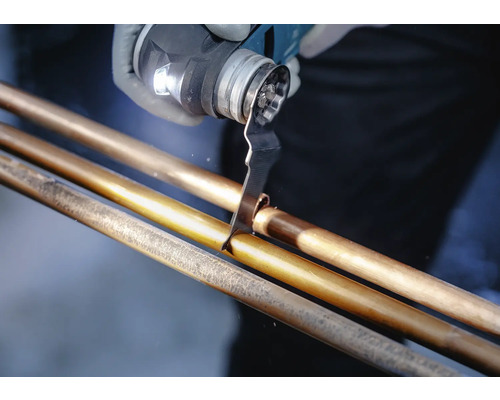 Eine Person schneidet mit einem Multifunktionswerkzeug ein Kupferrohr.