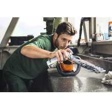 Mann sprüht Pflegespray auf eine Heckenschere, um die Klingen zu warten.