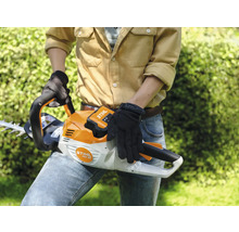 Eine Person hält eine Akku-Heckenschere der Marke Stihl.