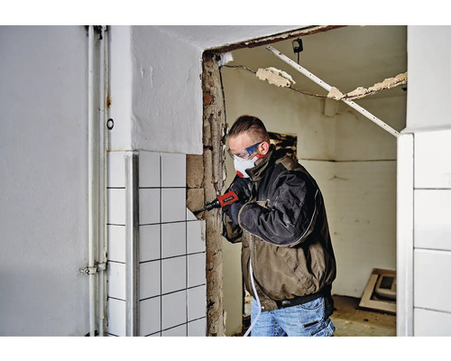 Mann entfernt Fliesen mit einem Elektromeißel in einem Raum.