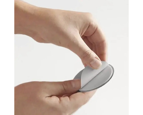 Eine Hand entfernt die Schutzfolie von einem Klebepad.