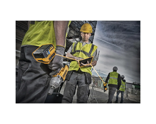Bauarbeiter mit gelbem DeWalt Akku-Schlagschrauber und Tablet auf einer Baustelle