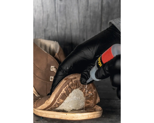 Auftragen von Klebstoff auf einen Schuh zur Reparatur der Sohle