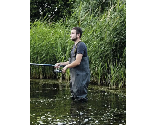 Angler mit Wathose steht im Wasser und hält eine Angelrute.
