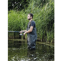 Mann fischt mit Wathose und Angel im Wasser vor Schilf