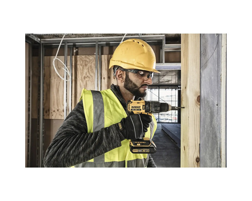 Ein Handwerker bohrt mit einem Akku-Bohrschrauber von DeWalt ein Holzbrett.