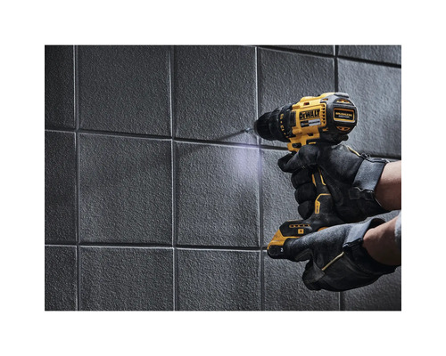 Eine Person bohrt mit einem Akkubohrer der Marke DeWalt in eine geflieste Wand.