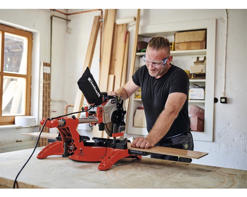 Mann mit Schutzbrille arbeitet mit einer Einhell Kapp- und Gehrungssäge in einer Werkstatt.