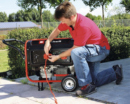 Ein Mann schließt ein Stromkabel an einen Einhell Stromgenerator an.