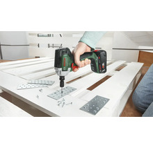 Eine Person verwendet einen Akku-Schlagschrauber zum Befestigen von Metallplatten an einer Palette mit Schrauben. Bosch Logo.