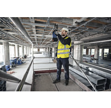 Handwerker auf einem Gerüst bei der Installation von Rohren und Leitungen an einer Decke.