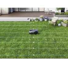 Ein Rasenmähroboter mäht einen Rasen in einem Garten mit Terrasse.